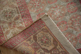Folded Belouch rug corner reveals distressed beige and faded raspberry pile with hand-knotted foundation.