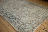 Corner view of a distressed Heriz carpet with a turtle border in charcoal, beige, and slate blue.