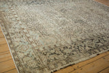 Angled corner view of a vintage Heriz carpet's geometric turtle border and visibly worn pile.