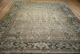 Low perspective on a vintage Heriz carpet highlighting its charcoal turtle samovar border and sand-toned field.