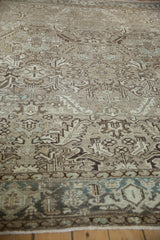 Worn, low pile of a vintage Heriz carpet with beige floral vines and a dusty teal border.