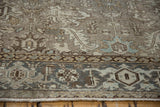 Close view of the worn knot heads and charcoal turtle samovar border on a distressed Heriz carpet.