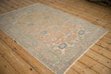 Distressed Kayseri rug, showing a traditional cartouche and floral arabesque border, pastel peach and dusty teal.