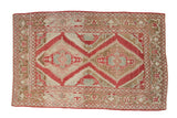 Distressed Caucasian rug with two serrated medallions in raspberry red, dusty bronze, and antique ivory.