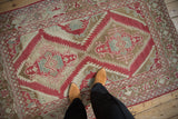 In-situ view of a distressed Caucasian rug highlighting its raspberry red geometric design and time-softened texture.