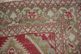Corner view of a Caucasian rug's boteh and palmette border in raspberry and bronze.