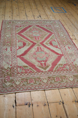 Low perspective on a distressed Caucasian rug, highlighting the raspberry red serrated medallions.