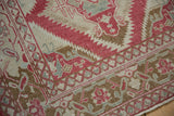Corner view of a vintage Caucasian rug's boteh and palmette border with time-softened pile.
