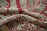 Softly draped Caucasian rug highlighting the time-softened texture of its red and seafoam motifs.