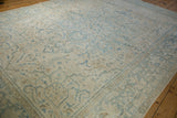 Angled view of a distressed Ahar carpet with time-softened powder blue and sand floral patterns.
