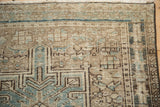Fringed corner of a distressed vintage Karaja runner, with geometric patterns in jade green and coffee brown.