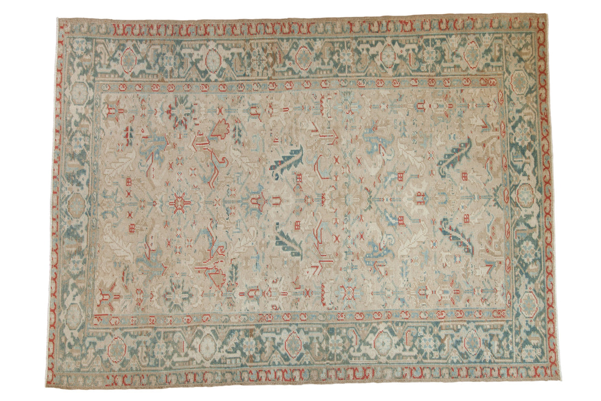 Vintage distressed Heriz carpet with an allover floral design in dusty teal and red on a neutral ivory field.