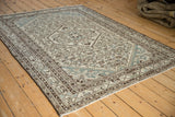 Distressed border and geometric Herati patterns of a vintage Hamadan rug with ivory, brown, and blue.