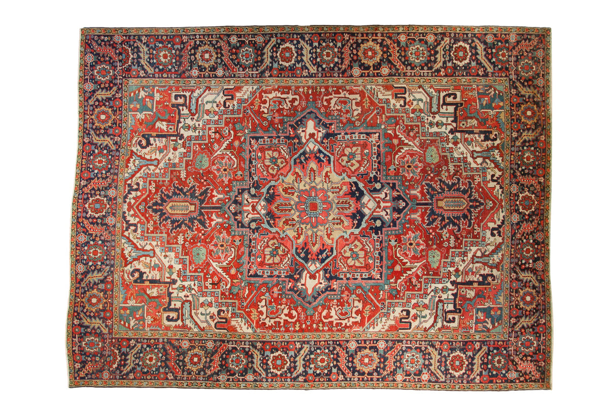 Vintage Heriz carpet with bold quatrefoil medallion, gem-tone red field, and intricate floral motifs.