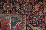 Vintage Heriz carpet border detail with serrated leaves, floral motifs in red, navy, and teal.