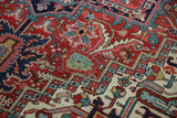 Complex ruby red, navy, and sand geometric floral design on a vintage Heriz carpet.