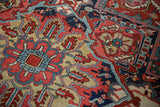 Vintage Heriz carpet featuring intricate ruby red and navy blue serrated floral patterns.