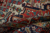 Folded vintage Heriz carpet showcasing hand-knotted gem-tone floral patterns in red, navy, and beige.