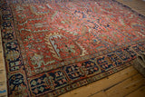 Heriz carpet corner with navy blue border, dynamic red field featuring expressive curvilinear motifs.
