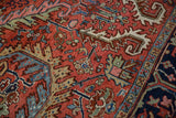 Madder root red field with intricate curvilinear Heriz design and navy blue border.