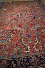 Navy blue border and red field of a vintage Heriz carpet with sprawling motifs.