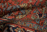 Folded hand-knotted Vintage Heriz pile with madder red, navy, and beige serrated leaves.