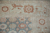 Corner view of a vintage Sparta carpet's floral motifs in slate blue-green, ivory, and pale copper.