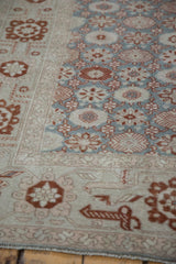 Angled view of a vintage Sparta carpet's ivory border and slate blue green floral field with low pile.