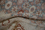 A fold in the vintage Sparta carpet shows the even texture of its hand-knotted pile and floral pattern.