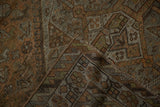 Distressed Kamseh rug corner, revealing worn wool texture, subtle geometric design, and rich chestnut selvage.