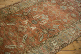 Heavily abrashed terracotta ground of a distressed Heriz rug with dusty teal blue and sand-colored motifs.