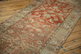 Angled perspective on the heavily abrashed terracotta field of a vintage Heriz runner.