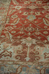 Angled close-up on the distressed Heriz rug's textured pile and abrashed terracotta field.