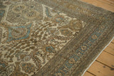 Corner detail of a distressed Ardebil carpet with sky blue and sand floral motifs on an ivory ground.
