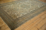 Perspective view along the distressed Ardebil carpet, showing its repeating medallions and intricate sand-toned borders.