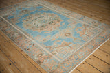 Angled view of a vintage Hamadan rug showing the large peach medallion and even wear on the sky blue field.