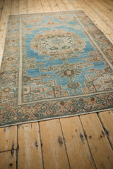 Angled view of a vintage Hamadan rug, showing its distressed low pile and decorative pattern.