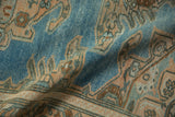 A fold in the distressed Hamadan rug reveals its low pile texture and even wear.