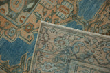 A distressed Persian rug corner folded over, revealing the hand-knotted back and worn pile.
