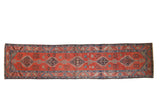 Antique Bakshaish runner with stepped diamond medallions in a single column on a madder red ground.