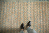 Vintage Hamadan rug detail: lattice germinating plant pattern with abrashes in sand, brown, and blue hues.