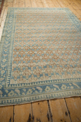 Corner of Hamadan rug, revealing denim blue pawn design border and sand lattice field.