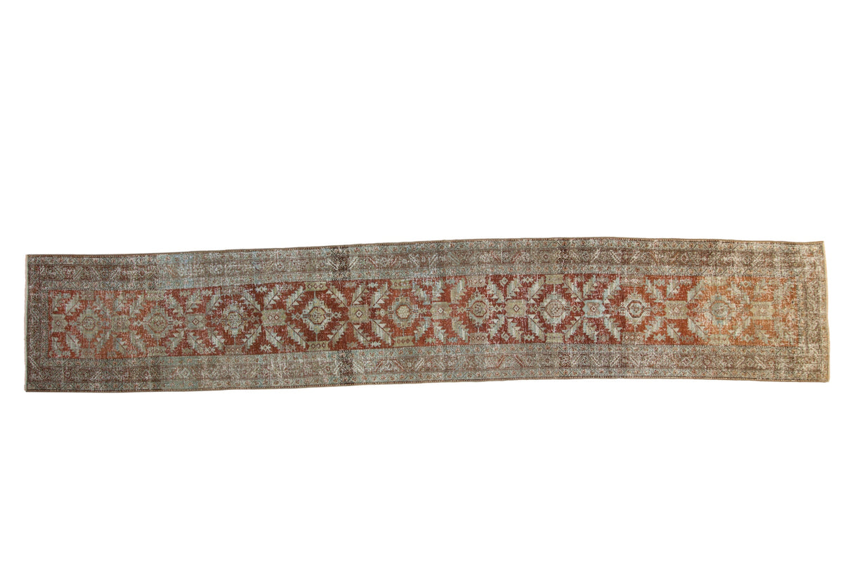 Distressed vintage Heriz rug runner with geometric palmettes in rust, terracotta, and faded powder blue.