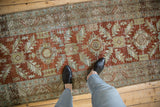 The decorative, time-softened wear on a vintage Heriz runner with geometric rust and blue designs.