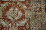 The distressed texture of serrated leaf and diamond palmette motifs in rust and blue.