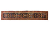 Antique Heriz rug runner with geometric cypress tree motifs on a navy blue field and brick red border.