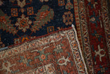 A Heriz rug's folded corner showing the hand-knotted back, pile wear, and polychromatic side cord.