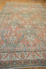 A low-angle view across the distressed vintage carpet, showing the melon and blue trellis pattern.