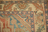 Hand-knotted corner detail of a distressed Persian rug with ivory, red, and sapphire blue borders.
