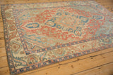 Angled view of a vintage Baktiari rug showing the geometric patterns in red, blue, and sand tones.